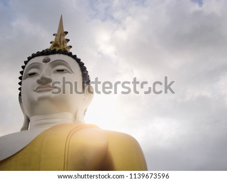 Photographs only of the head of a large statue of the Buddha and the sky is covered with clouds.