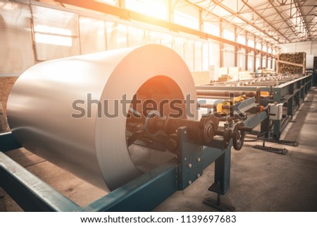 Industrial galvanized steel roll coil for metal sheet forming machine in metalwork factory workshop, sunlight toned Royalty-Free Stock Photo #1139697683