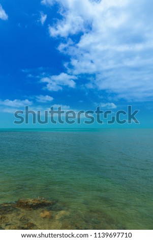 Seascape beach sand and rocks, turquoise water and blue sky