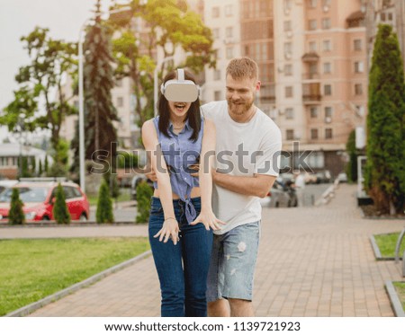 A young couple plays a game using virtual reality glasses on the street. VR headset