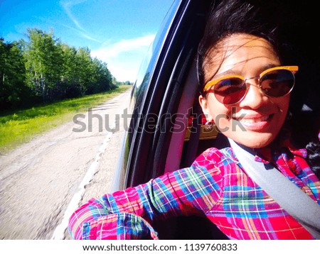 A woman taking selfie from passenger seat of car vehicle of rural landscape in a background in Alberta, Canada.