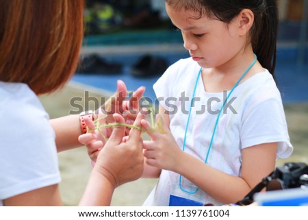 5-6 years old Asian little girl playing string game with her mother.Hands Playing String Game Creativity.A popular string game is cat's cradle or rabbit's cradle.Girl enjoy and fun.Creative thinking.
