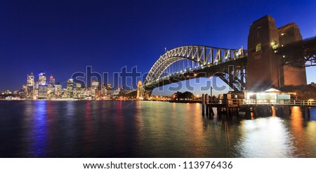 Sydney city CBD view across harbour along Bridge illuminated at sunset lights reflected in water australia landmarks