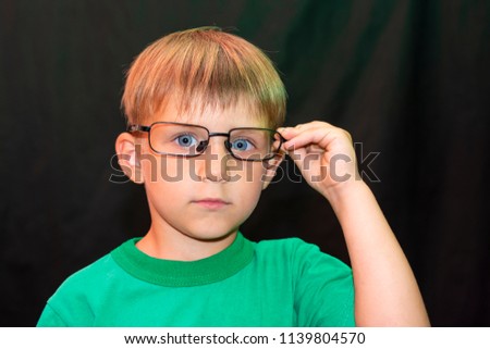 Casual boy in glasses shows different faces to the camera on a dark background