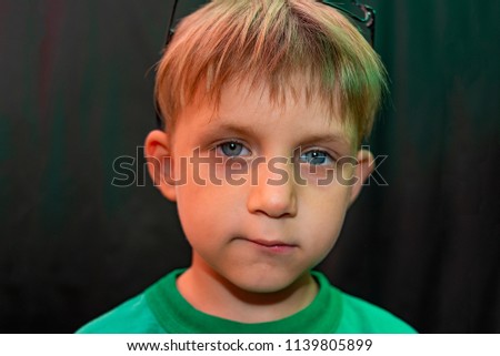 Casual boy in glasses shows different faces to the camera on a dark background