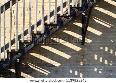 Close up view of an urban brick building fire escape staircase casting late day shadows
