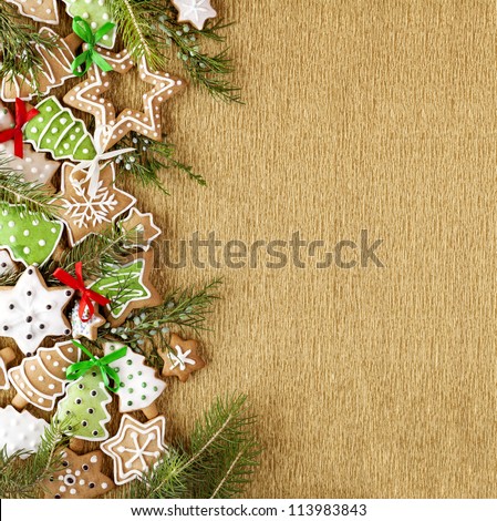 Christmas Ginger and Honey colorful cookies with fir tree branches and bows on the gold wrapping paper background.
