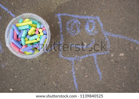 crayons on the asphalt in a bucket with a picture