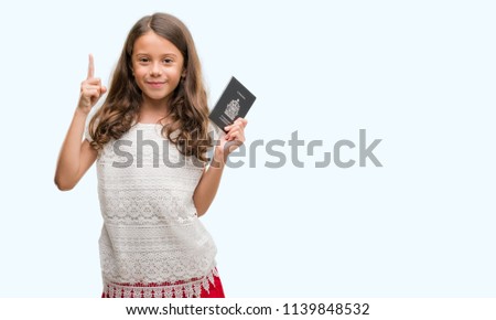 Brunette hispanic girl holding passport of Canada surprised with an idea or question pointing finger with happy face, number one