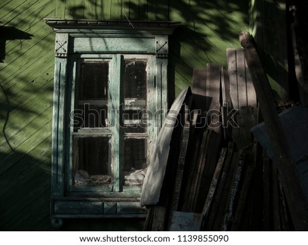 Old blue window frame on wooden wall. Green log house detail with timbers. Village outdoor background. Old timber texture in sunlight wallpaper. Countryside outdoor photo. Natural timber surface. 