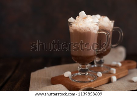 Two glasses with Hot chocolate garnished with whipped cream, marsmallow and cocoa powder. Winter and autumn time. Christmas drink