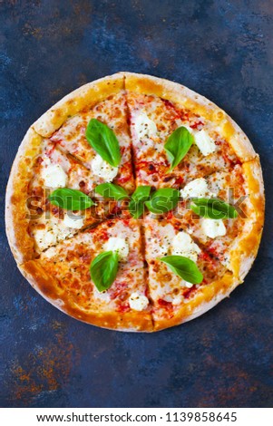 Homemade hot pizza with tomatoes, mozzarella and basil. Top view with copy space on dark stone table.