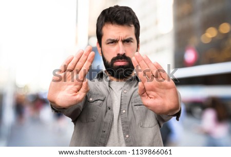 Handsome man with beard making stop sign at outdoor