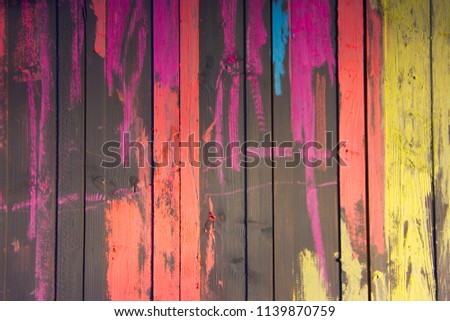 The wooden wall is decorated with colorful crayons. Texture of a tree and multi-colored chalk.