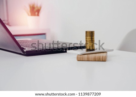 Gold coins are on the phone. The concept of financial growth, earning thanks to telephone, mobility. Mobile profit center. A view of the office, telephone, laptop and gold coins.