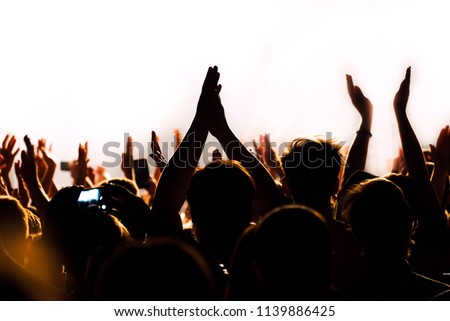 Hands raised up in a colorful stage lights of night club show