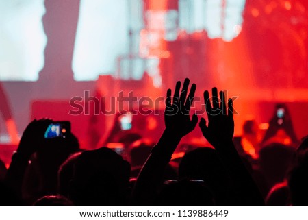Hands raised up in a colorful stage lights of night club show
