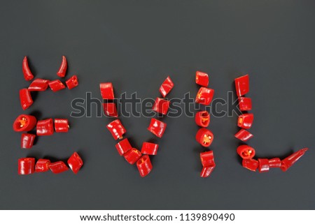 Evil with horns- word written with fresh hot chilli peppers. Top view. Chile letters of pepper. Bad seeds