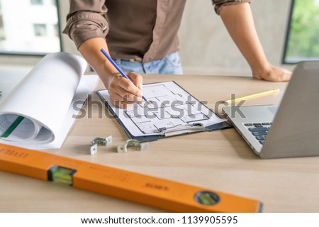 Asian civil engineer,architecture checking blueprint in tablet at working site.blue print is fake only for stock photo.
