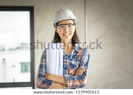 Asian woman civil engineer,architecture holding blueprint at working site.blue print is fake only for stock photo.

