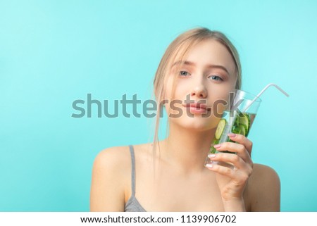 Caucasian female face with towel on head pressing tightly to her cheel glass of cold cucubmer and mint coctail. Beauty salon concept. Skin and hair care. Royalty-Free Stock Photo #1139906702
