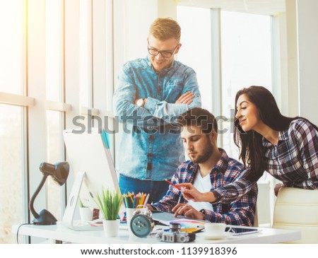 Side view of three creative designer artists working on computer at the office