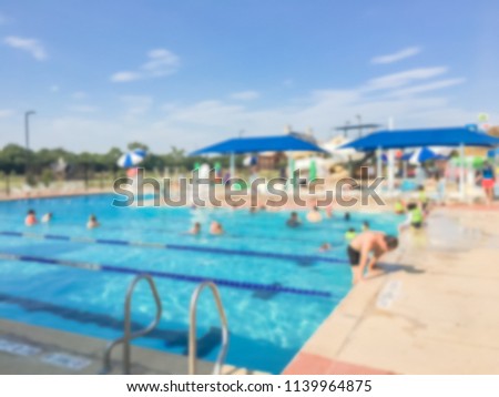 Blurred children and their parents enjoy swimming and water activities at community outdoor swimming pool. Healthy lifestyle, active parent, swim lesson activity, family vacation at aquatic center Royalty-Free Stock Photo #1139964875