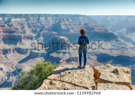 Girl in Jeans Suite is Standing on the Edge of Grand Canyon