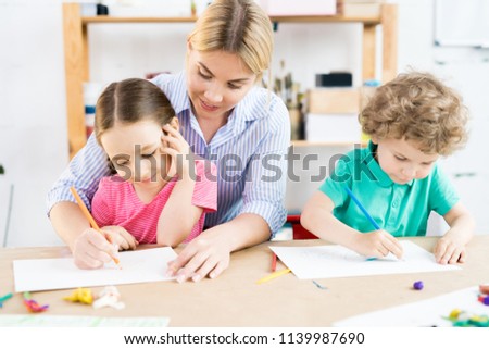 Young mother teaching her children to write an alphabet