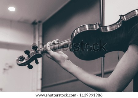 Female musician's hand on the strings of a violin in black and white.