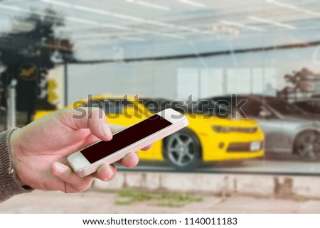 Man use mobile phone, blur image of a super car as background.