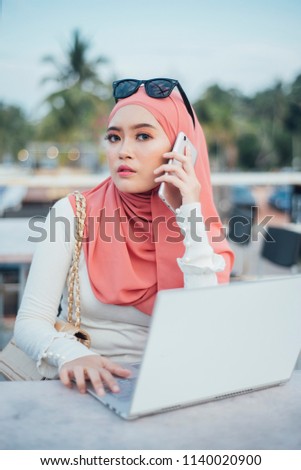 Young arab woman wearing hijab happy talking using a smartphone mobile phone