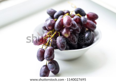 Bowl with pink grapes on white background