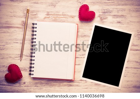 Blank photo frame and notepad on wooden table