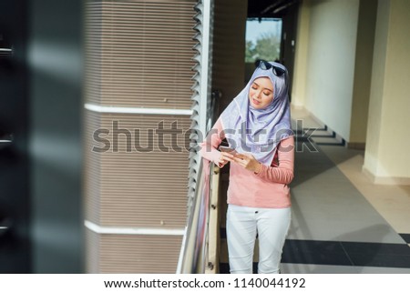 muslim teen wearing a head scarf using a phone