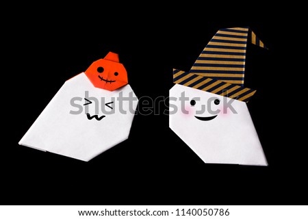 Origami for kids : Happy white ghost with pumpkin head jack lantern and witch hat made from folded paper on black background isolated.Top view, flat lay.Easy to use for card.Happy halloween.