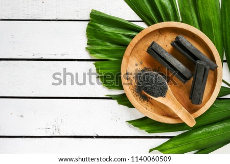 Bamboo charcoal and powder on wooden table. copy space Royalty-Free Stock Photo #1140060509
