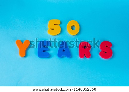 50 years old celebrating classic logo. Colored happy anniversary 50 th colored numbers on blue background. Greetings celebrates card. Traditional digits of ages. Flat lay . Royalty-Free Stock Photo #1140062558