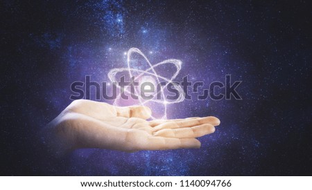drawn atom model above man hand at abstrac tgalaxy background