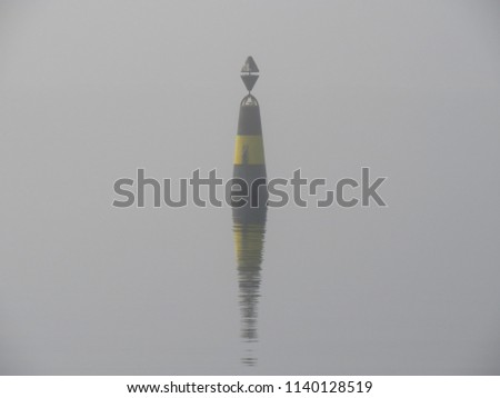 Buoy on the calm sea surface in fog