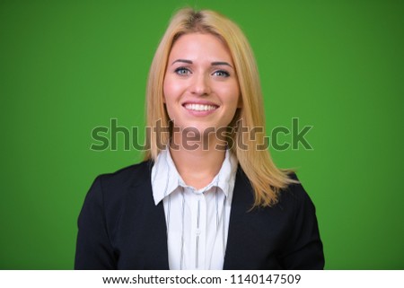 Young beautiful blonde businesswoman against green background