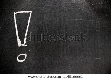 White color chalk hand drawing in exclamation mark with blank space shape on blackboard background
