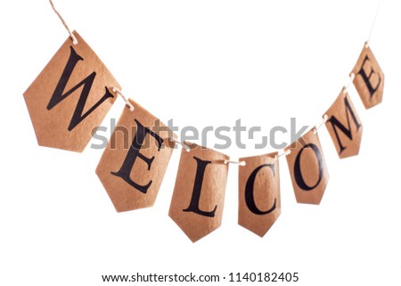 Welcome banner. Welcome text hanging on bunting in selective focus against white background. 