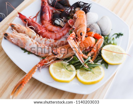 Gourmet restaurant seafood dish with langoustines, shrimps and clams decorated arugula and lemon 