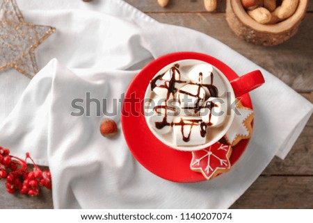 Cup of hot cocoa with marshmallows and cookies on table