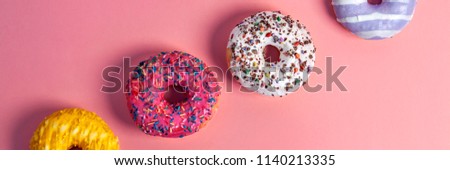 Millennial pink smooth background with colorful donuts on the diagonal