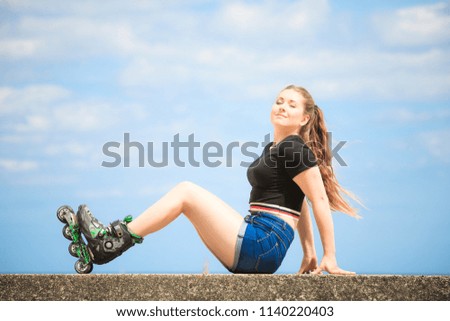 Happy joyful young woman wearing roller skates relaxing after long ride. Female being sporty having fun during summer time near sea.