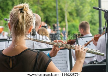 Girl playing the flute in the park. woman playing flute. game on a musical instrument flute at event. flute is close-up