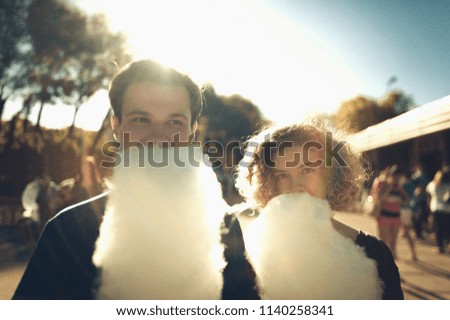 Smiling young couple in love with cotton candy in amusement park. Vintage filter photo