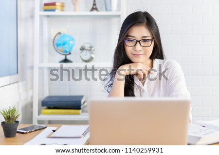Education study abroad,Asian student girl with glasses look at laptop while doing homework making video call abroad using internet friend connection, business women use computer analysis finance data  Royalty-Free Stock Photo #1140259931